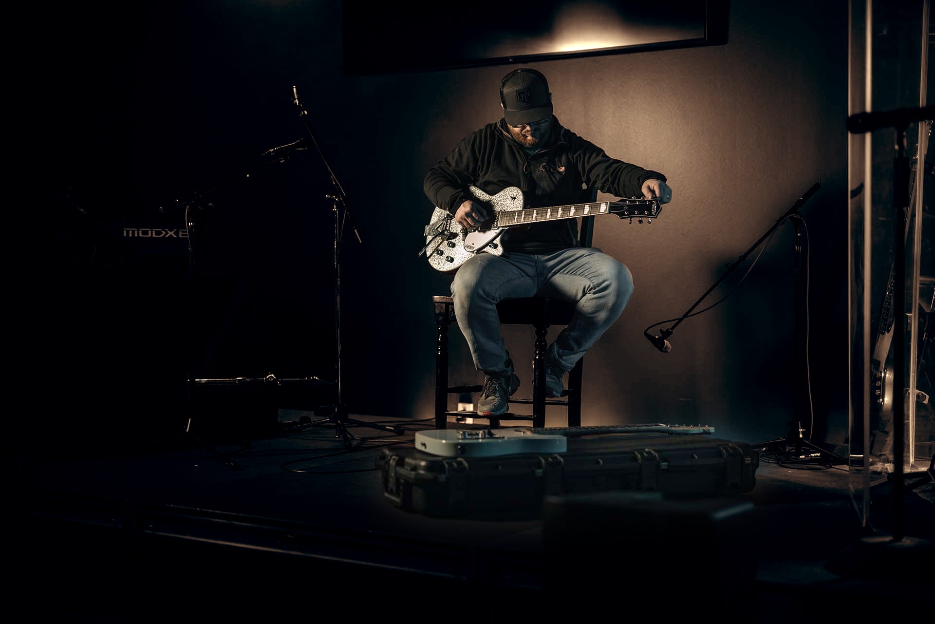 Person playing guitar on a dark stage with minimal lighting