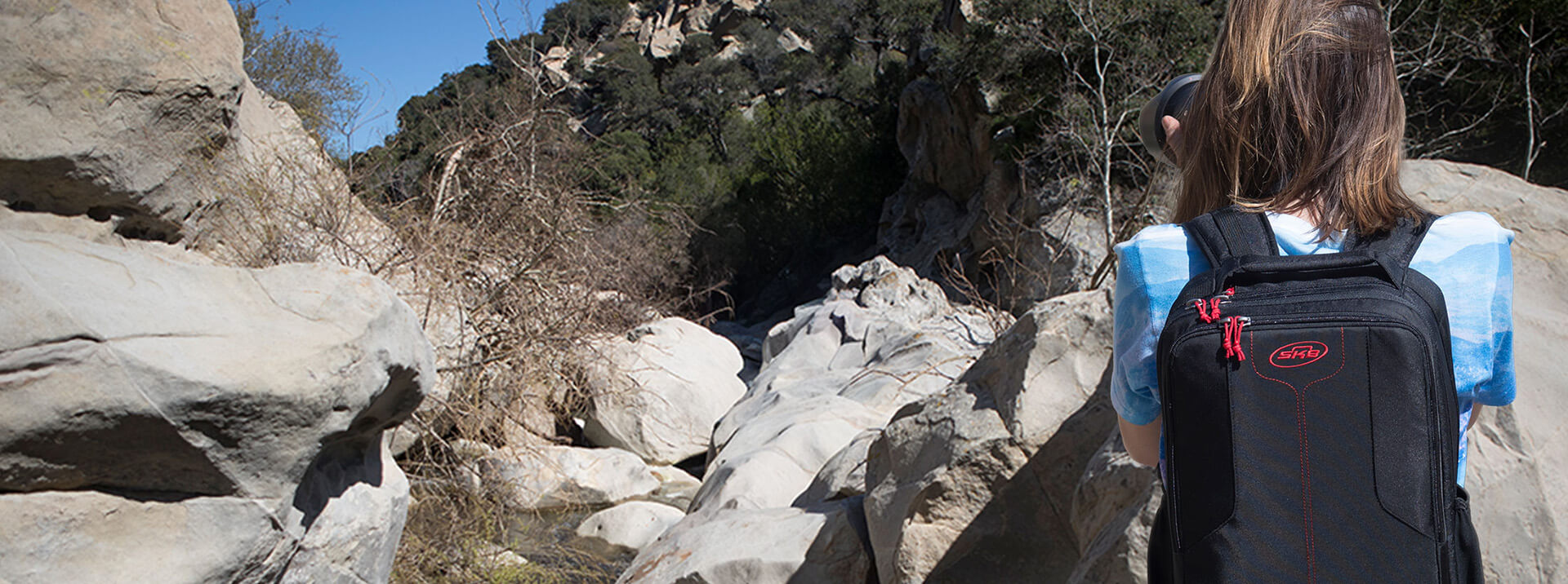 Person with a black backpack walking through a rocky landscape