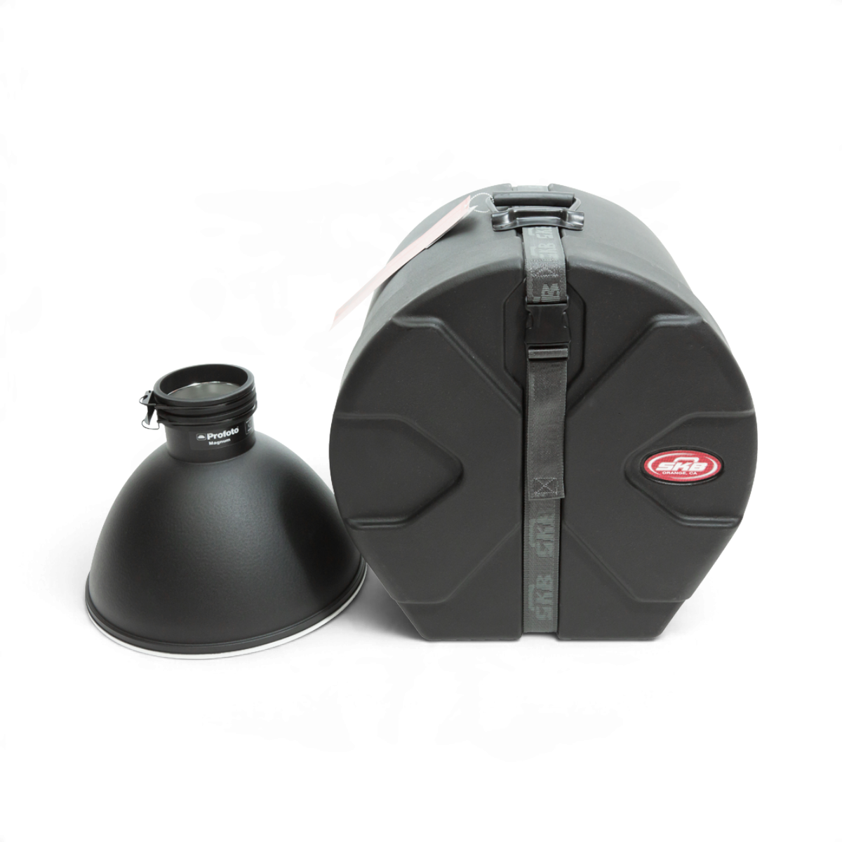 SKB Cases 12x12 roto-molded black drum case with Roto-X pattern and sure grip handle next to a Profoto Magnum reflector